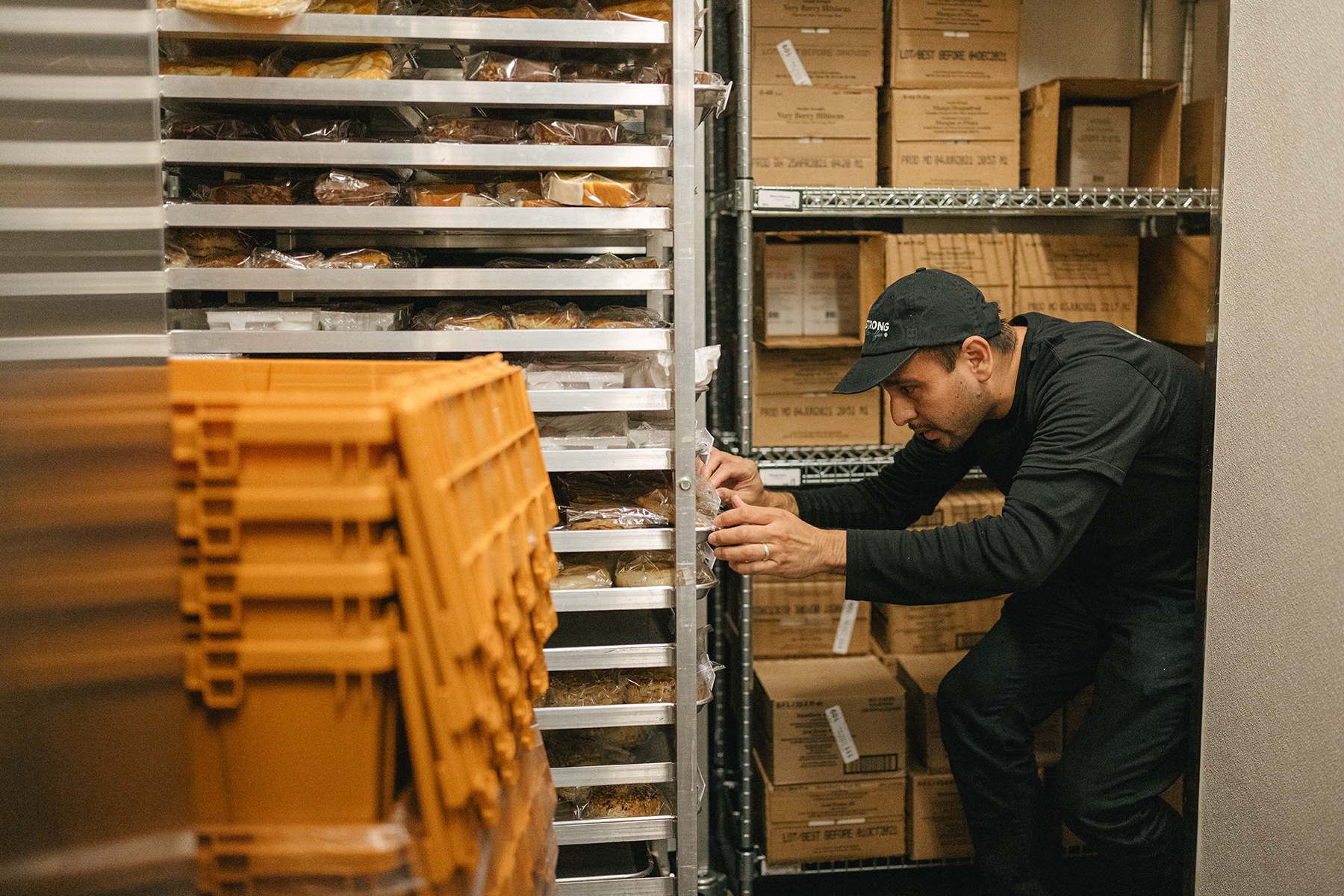 Antonio Flores Sanchez, Starbucks store manager, checking dates on a rack of food and pastries in the back room.