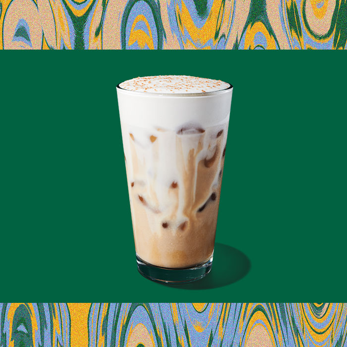 Iced White Chocolate Mocha with Pistachio Cream Cold Foam in clear glass on a green background
