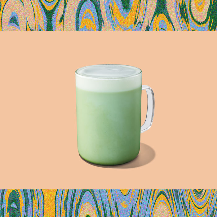 Hot Matcha Latte in a clear glass on a light orange background