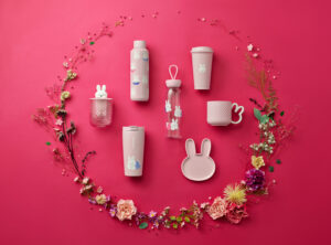 A collection of Starbucks tumblers and mugs in light pink colors on a red background with flowers