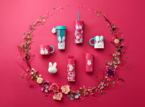 A collection of Starbucks tumblers and mugs in red, light green, white and light pink colors on a red background with flowers