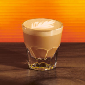 Starbucks hot honey cortado in a small glass on an orange background
