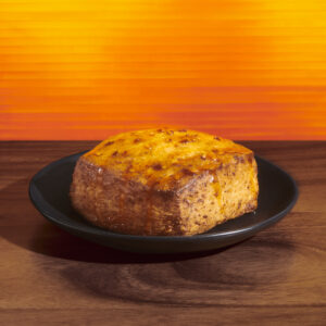 Starbucks reserve hot honey scone on a black plate on an orange background