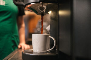 Black coffee being poured in a white Starbucks mug