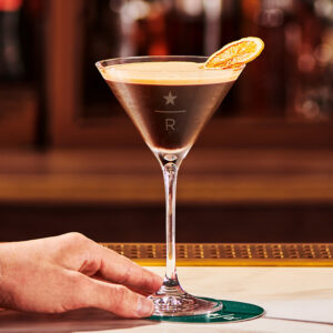 A hand with an espresso martini glass