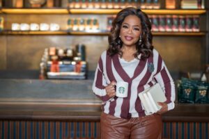 Oprah standing in a Starbucks store holding a Starbucks mug and books