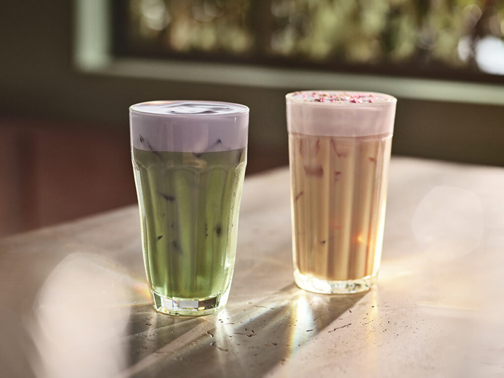 Two glasses one with iced matcha with lavender and another with iced cherry chai