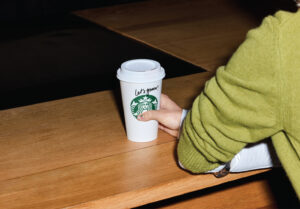 Woman's hand holding a Starbucks to-go cup with "Let's goooo!" written in Sharpie