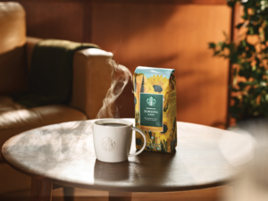 A mug with hot coffee next to Starbucks Sunsera coffee bag