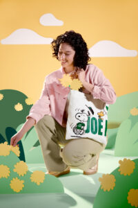 A female holding a tote bag for Starbucks and Peanuts collaboration