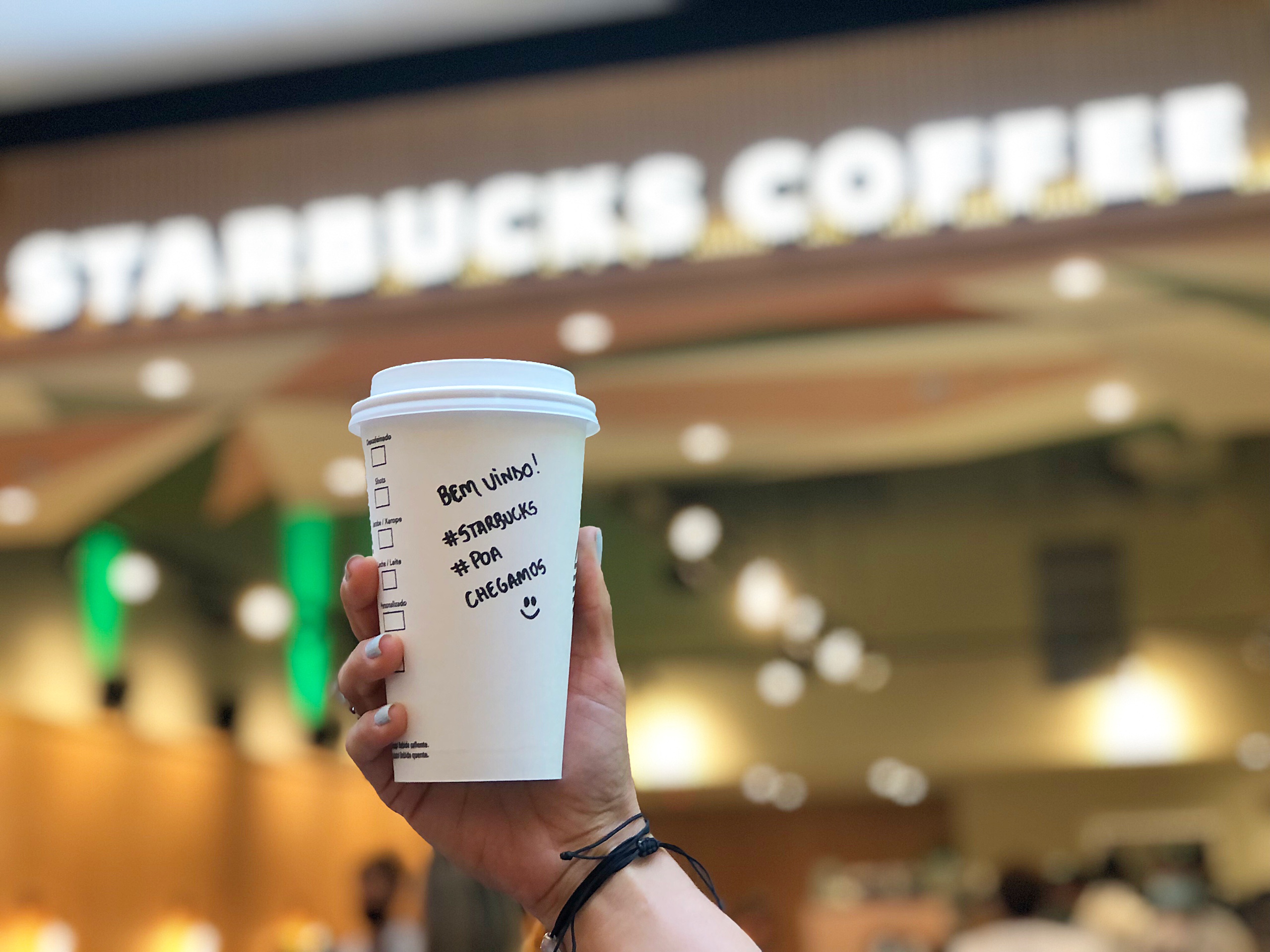 Person holds up Starbucks cup with writing on it